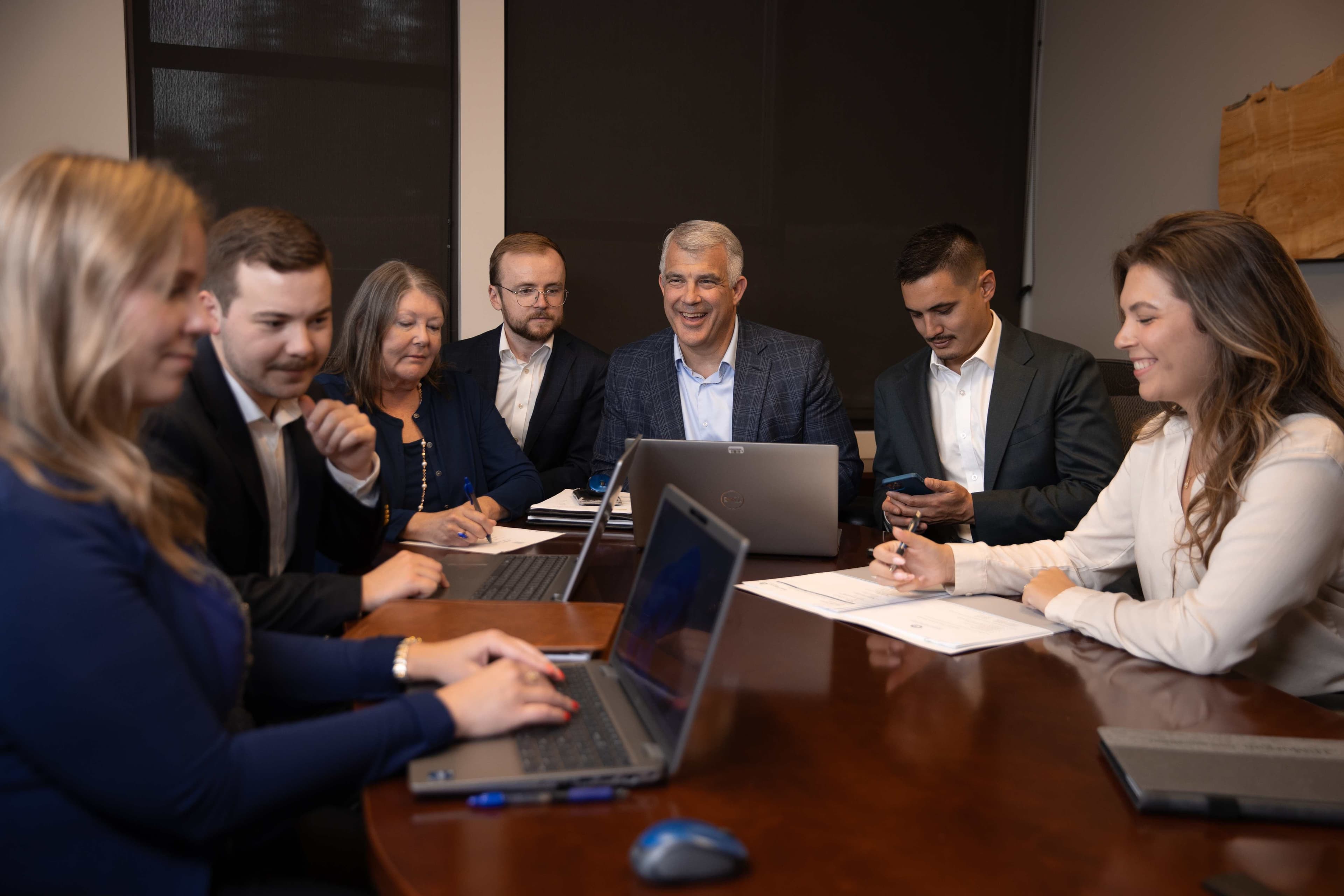 Professional photo of AMPF team members in a business meeting around a conference table with laptops