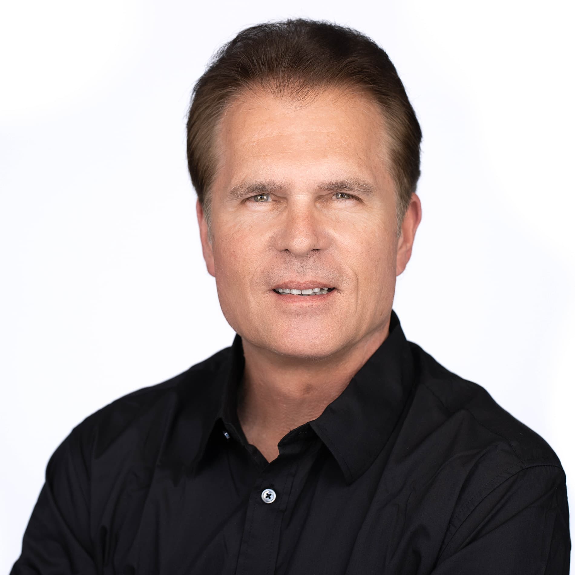 Professional headshot of middle-aged man with brown hair in a black button-up shirt against a white background