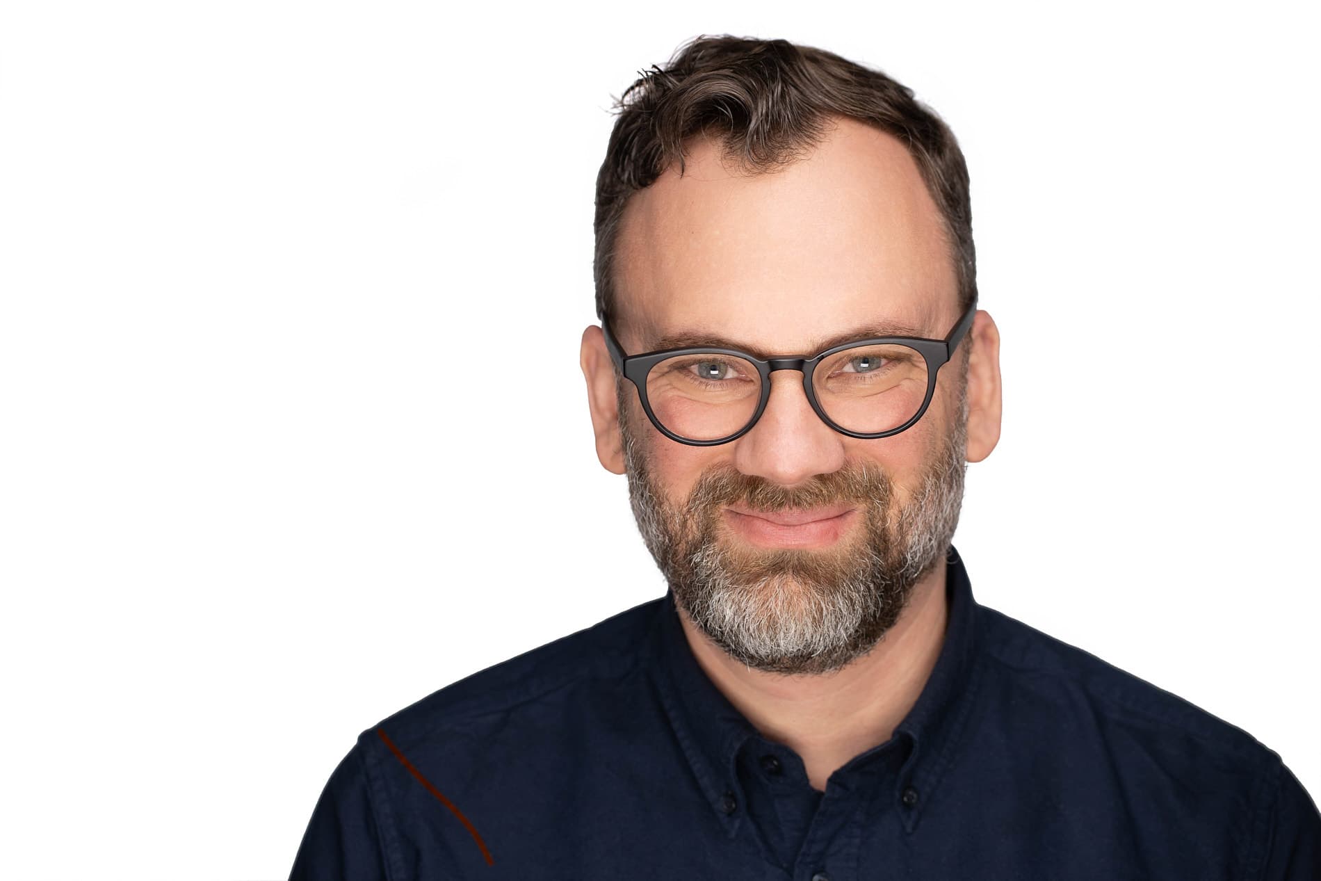 Professional headshot of a man with glasses and beard in a navy button-up shirt against a white background