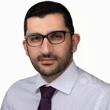 Professional headshot of man with glasses and beard in white shirt and tie