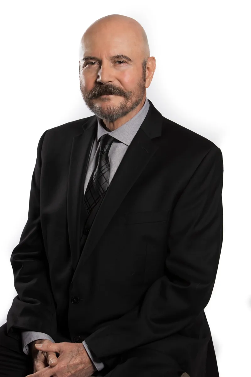 Professional headshot of bald man with mustache in suit
