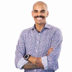 Professional headshot of a bald man with a mustache and earrings wearing a floral patterned shirt